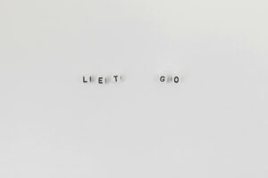 Minimalist composition featuring 'Let Go' spelled with letter dice on a clean white background.